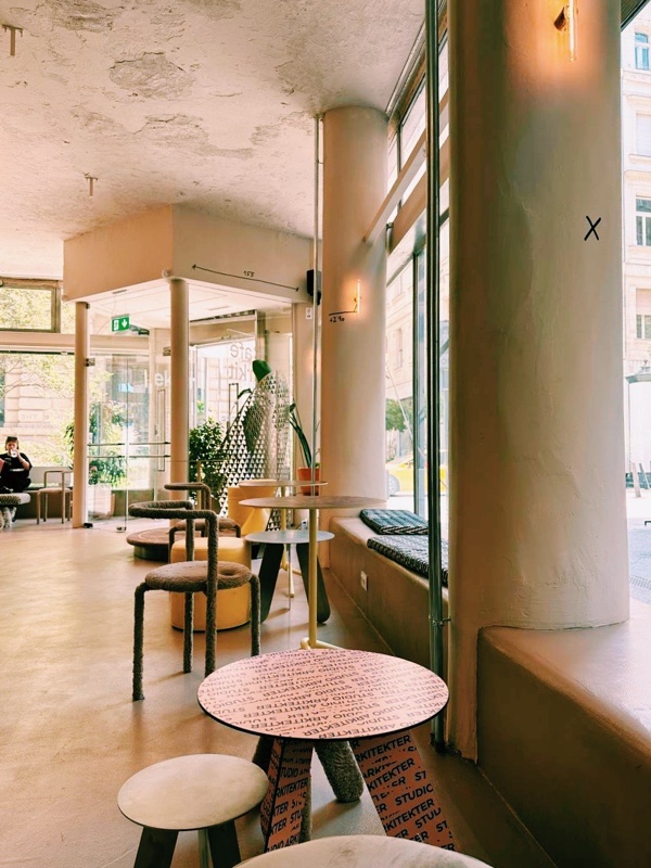 Café Arkitekter interior — columns, branded pink tables and large windows