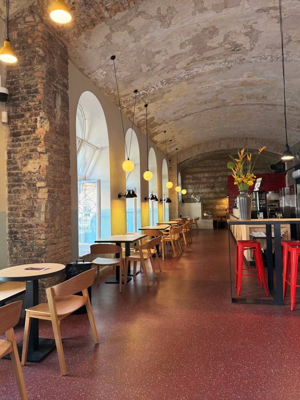 Coffee Capital hall — arched vaults, wooden tables and yellow pendant lights