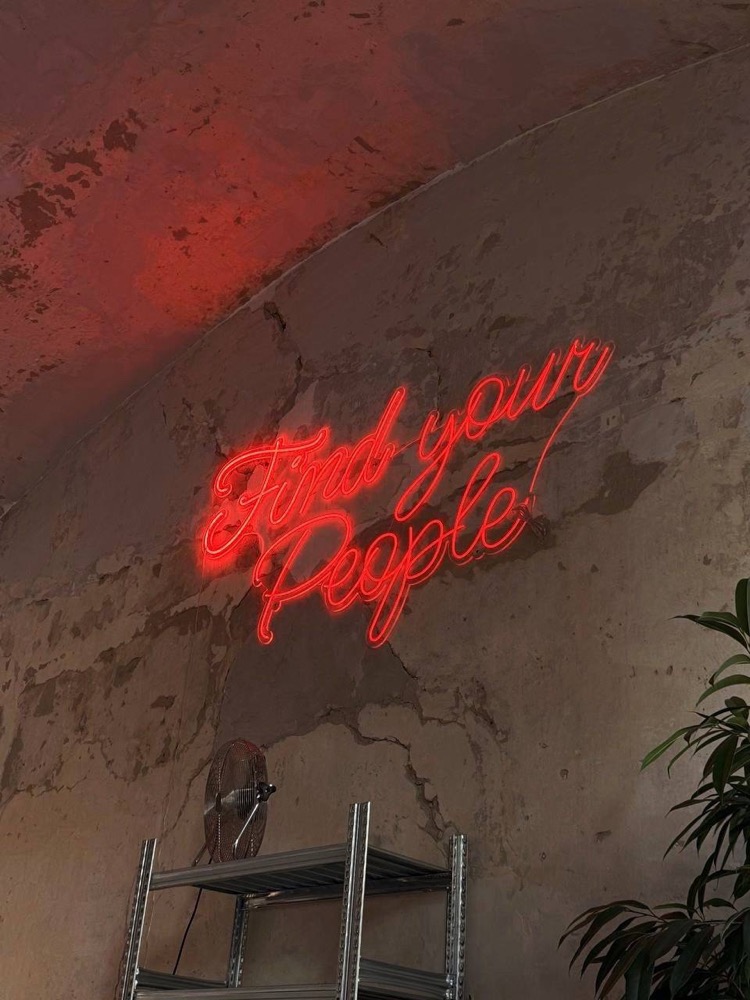 Find your People neon sign on a brick wall