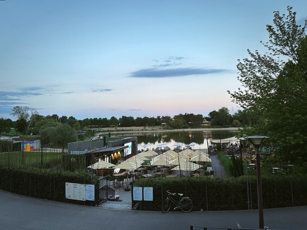 FLAVA beach from above — yellow striped umbrellas, waterfront and an outdoor screen at dusk
