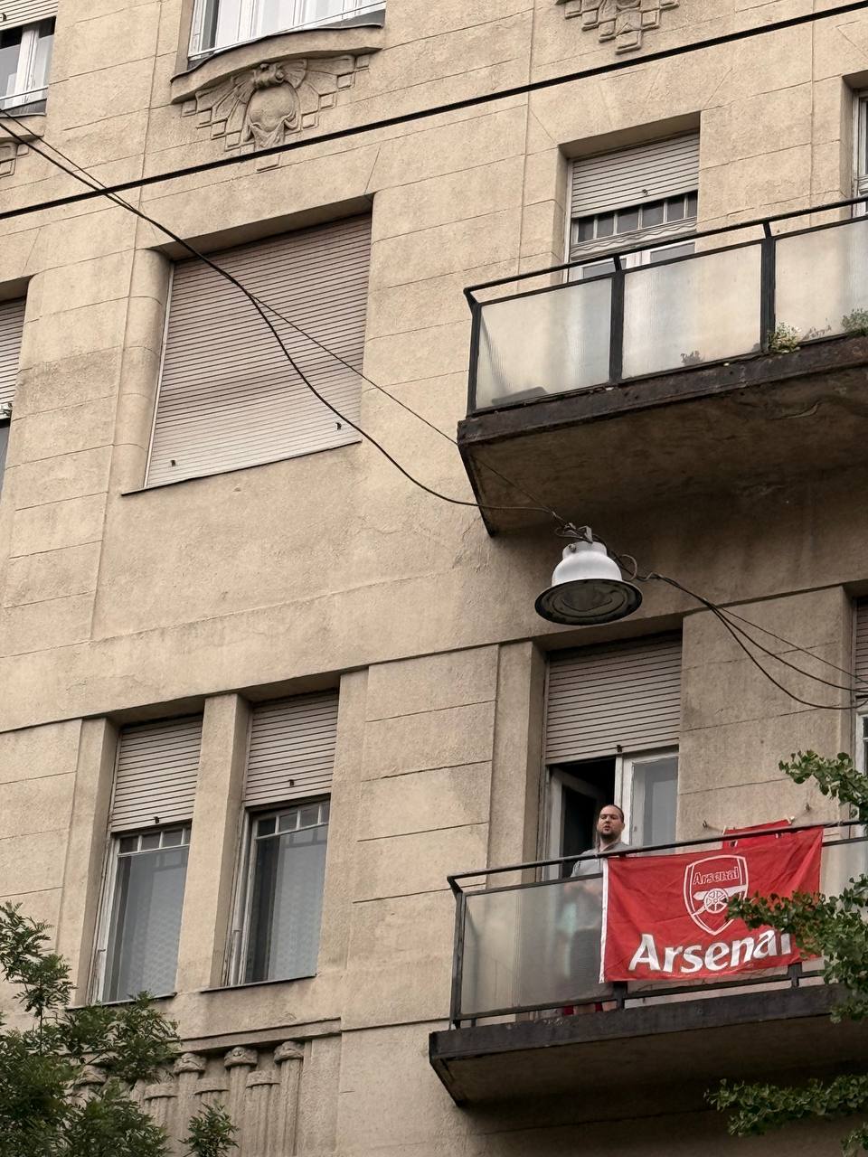 Arsenal fan with a flag on a Budapest apartment balcony